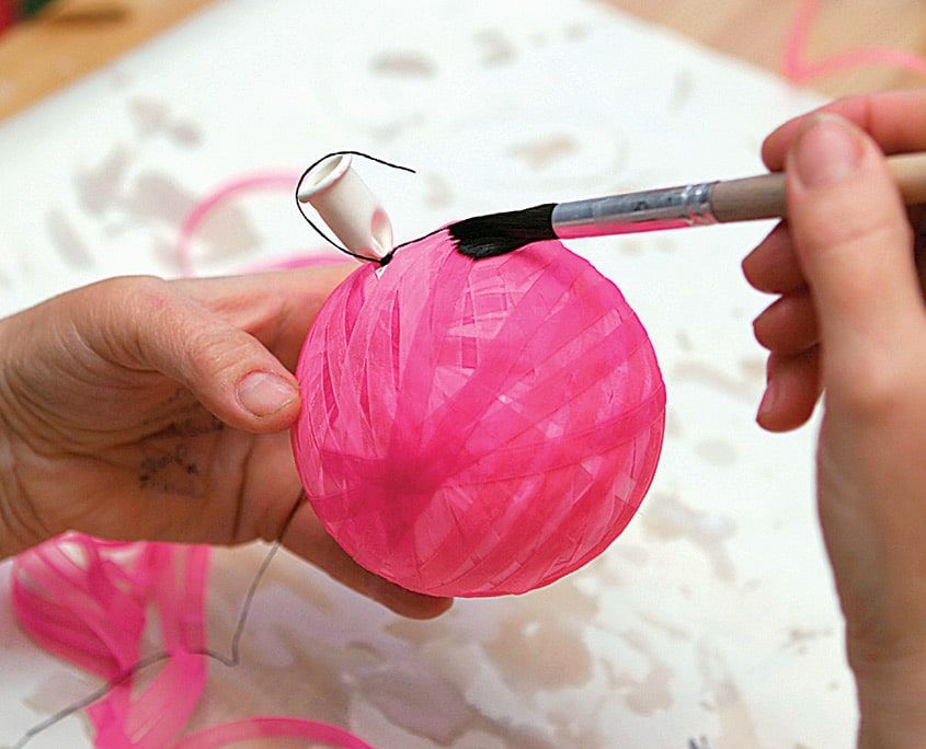 Pembe kurdeleyle sık sarılmış balon fırçayla baştan sona yapıştırıcıyla kaplanıyor