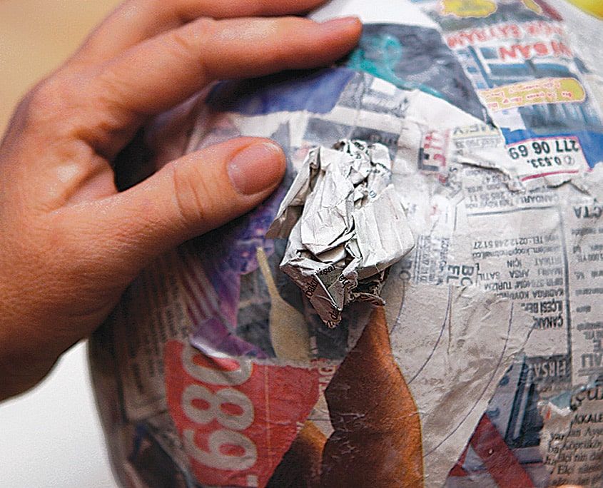 Balonun üzeri gazete kağıdı parçalarıyla kaplanıyor, buruşturulmuş kağıttan burun çıkıntısı ekleniyor