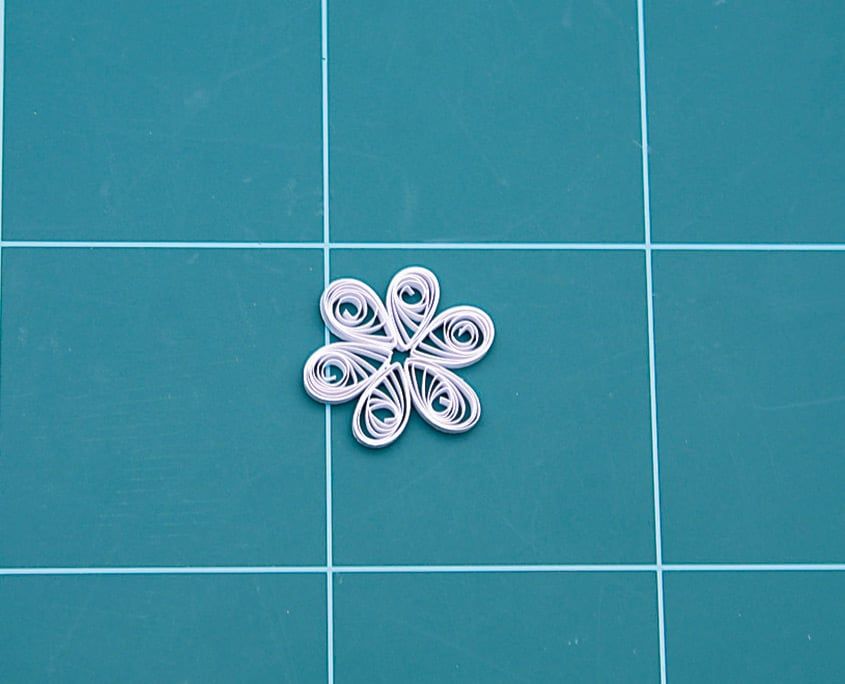 Altı beyaz damla quilling yaprağı yan yana dizilerek papatya çiçeği biçimi oluşmuş