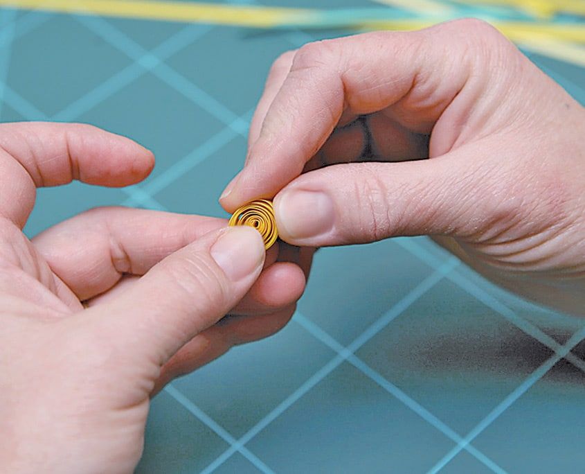 Gevşek sarı quilling spirali parmaklarla sıkıştırılarak taç yaprağı biçimine getiriliyor
