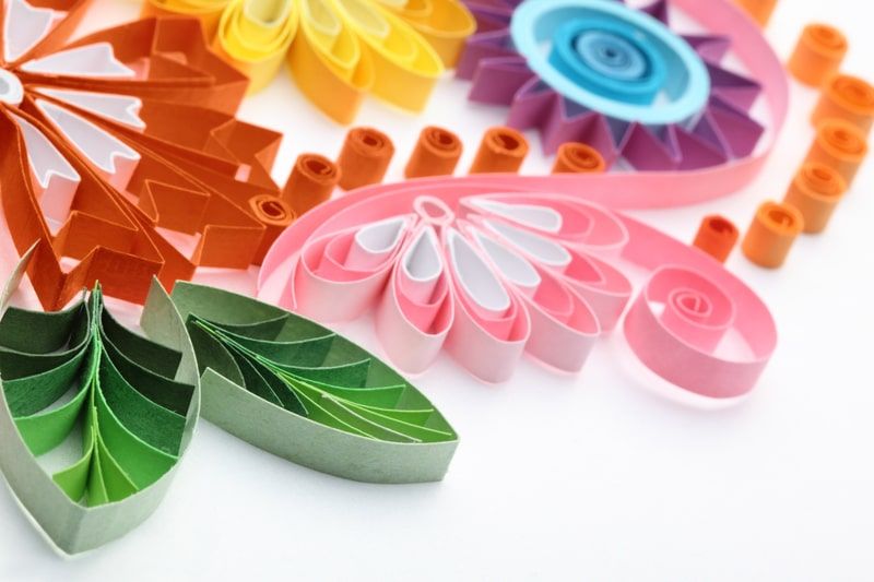 Quilling nedir: turuncu, pembe, mavi ve yeşil ince kağıt şeritlerden dolanmış çiçek ve yaprak motifleri
