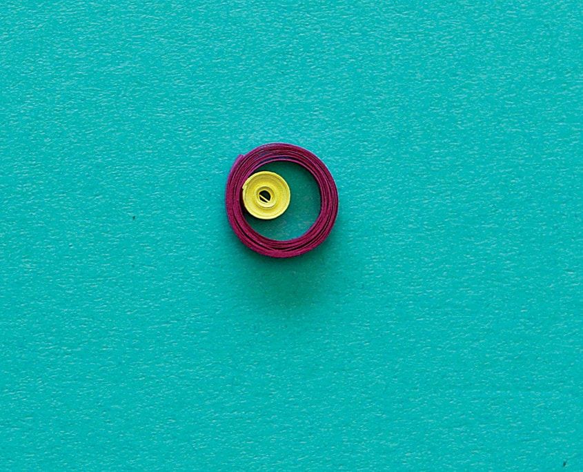 Turkuaz zemin üstünde bordo halka içine yerleştirilmiş sarı gevşek quilling spirali