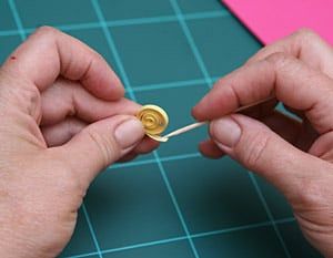 Kesim matı üzerinde iki elin sarı kağıt şeridi dolama aletine sararak sıkı bir rulo oluşturması