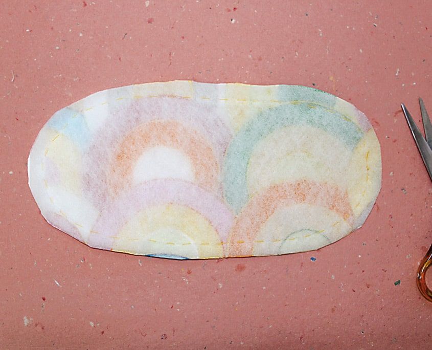 Oval biçimli taban parçası vatka ve desenli kumaştan kesilmiş, yanında makas