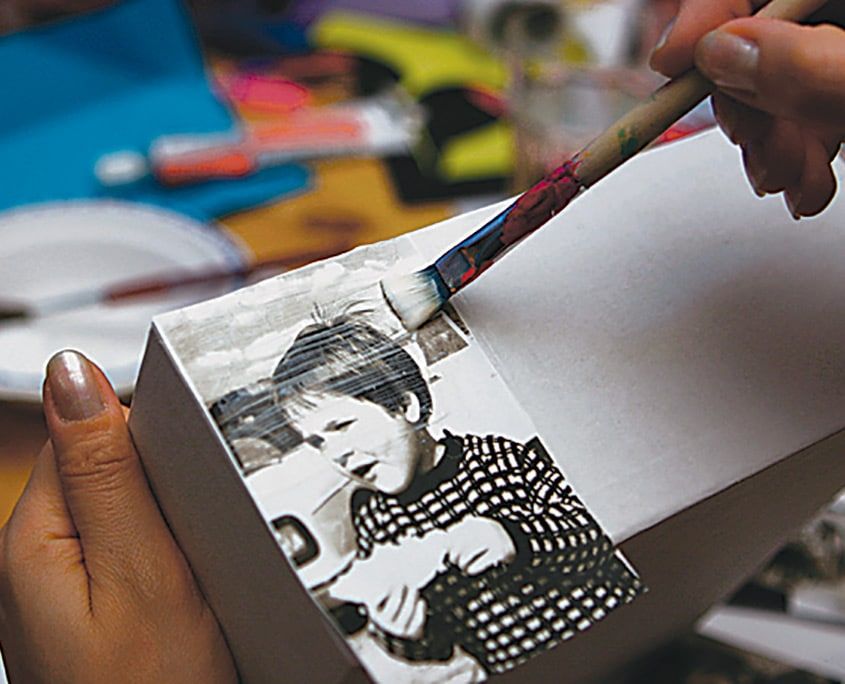 Kutuya yapıştırılan fotoğrafın üzeri fırçayla yapıştırıcı katmanıyla kaplanıyor