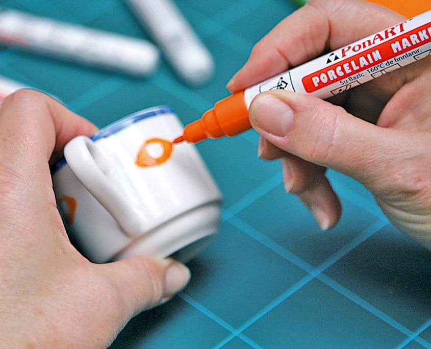 Kulplu fincana turuncu porselen kalemiyle göz bebeği boyanıyor