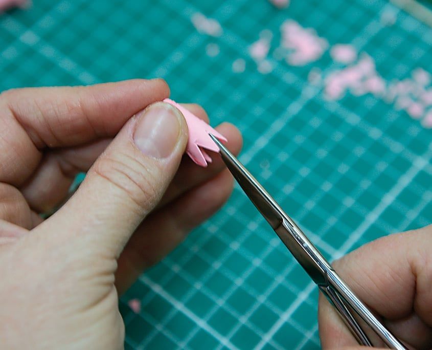 Pembe çan biçimli rulonun ağız kenarı makasla kesilerek sivri taç yaprakları açılıyor