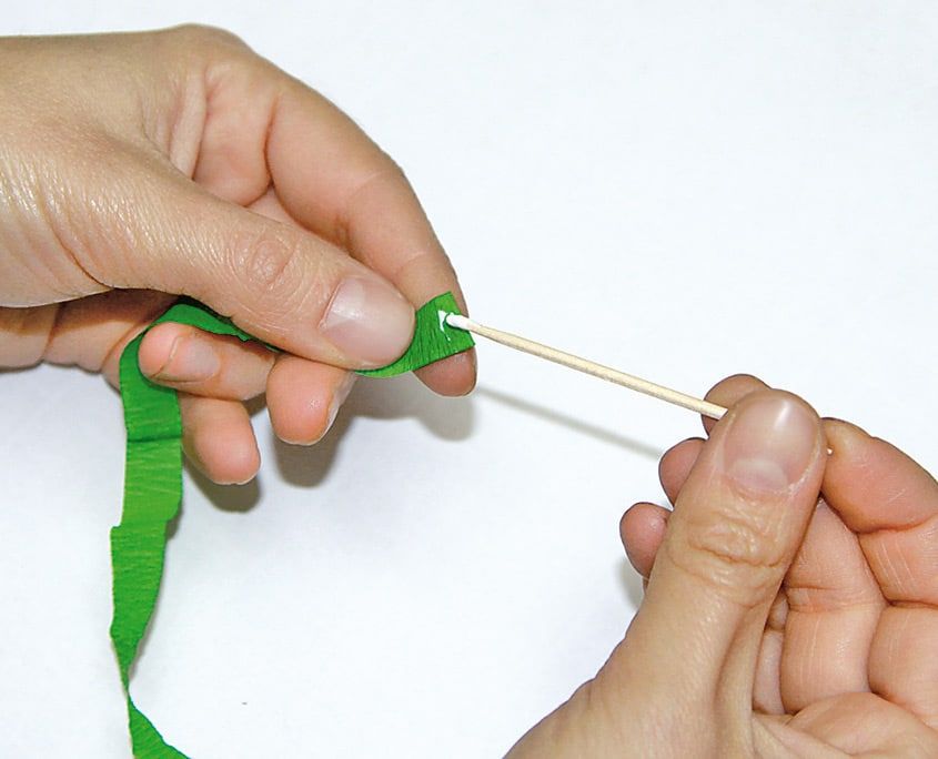 Yeşil krepon şerit ince tahta çubuğun çevresine sarılarak lale sapı hazırlanıyor