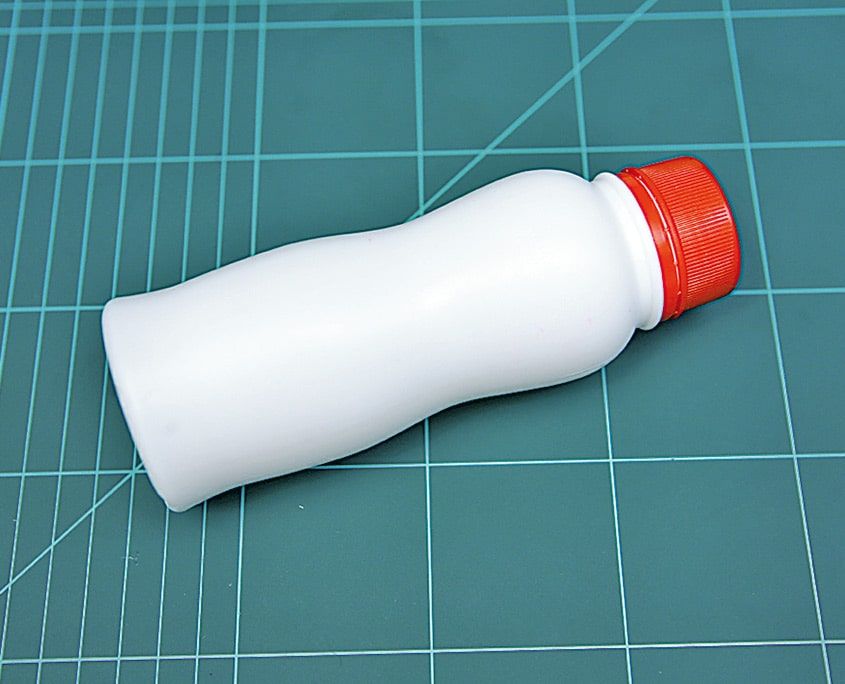Kesim matı üzerinde turuncu kapaklı boş beyaz plastik şişe, arabanın gövdesi olacak