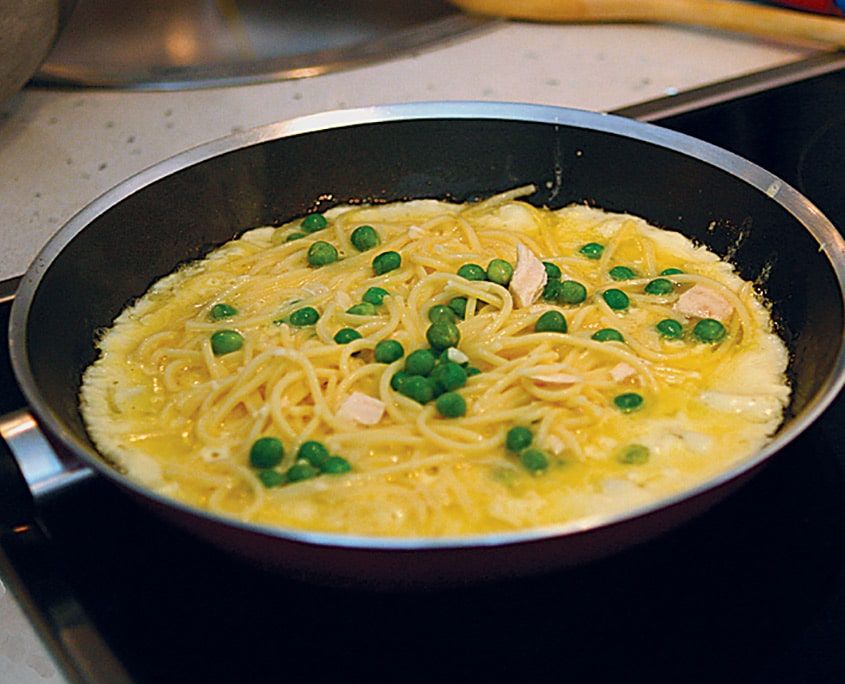 Tavada pişen makarnalı pancake: yumurtaya bulanmış tel makarna, bezelye ve tavuk parçaları