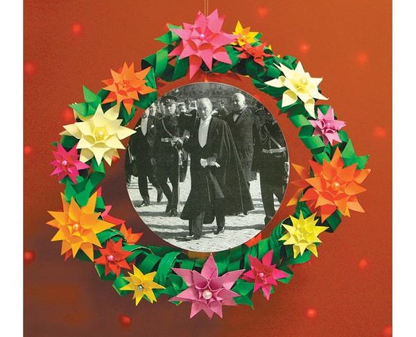 Çiçek çelengi: yeşil kağıt halkaya dizilmiş renkli yıldız kağıt çiçekler, ortada siyah-beyaz Atatürk fotoğrafı