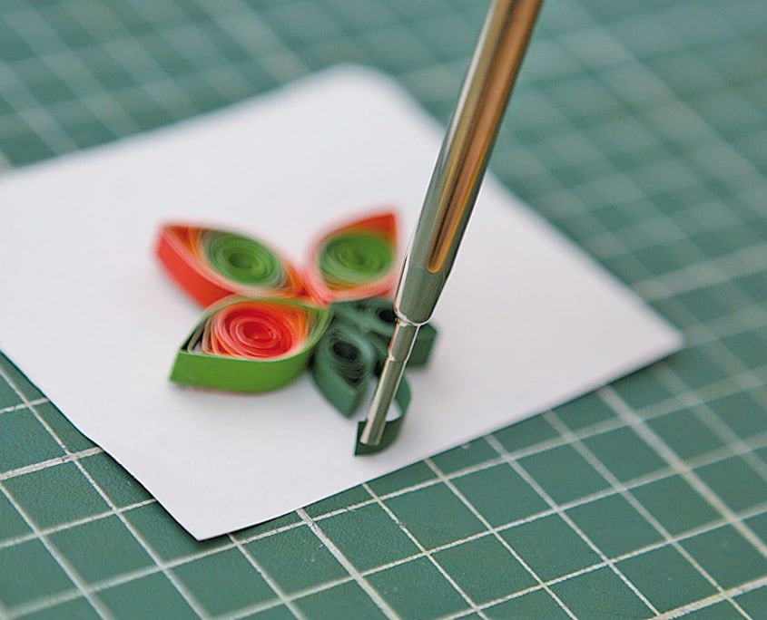 Quilling çiçeğin sapındaki kıvrım dolama aletinin ucuyla şekillendiriliyor