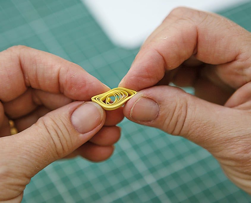 Sarı quilling rulosu iki ucundan sıkıştırılarak göz biçimine getiriliyor