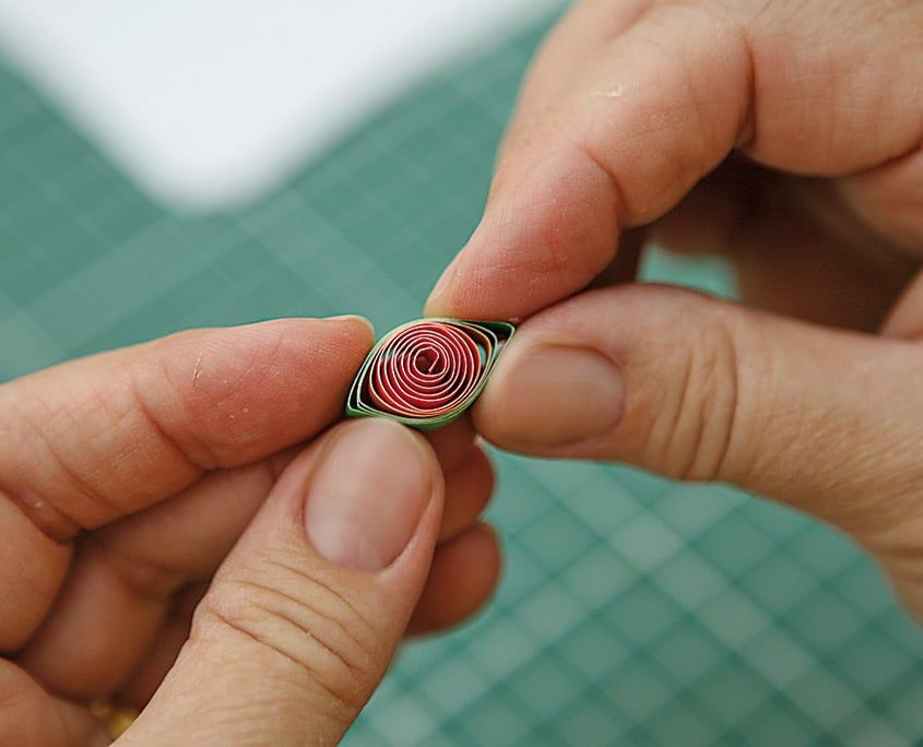 Parmaklarla iki ucundan sıkıştırılarak göz biçimi verilen kırmızı-yeşil quilling parçası