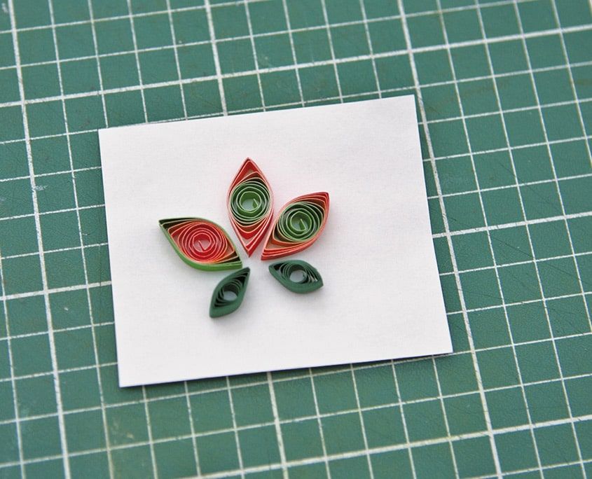 Beyaz kart üzerine dizilmiş kırmızı-yeşil göz biçimli quilling parçalarından yapılmış lale motifi