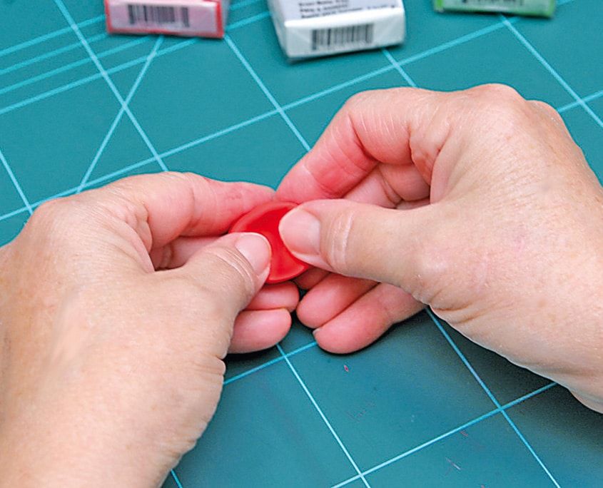 Kırmızı kil disk iki elle kenarlarından kıvrılarak bere biçimi veriliyor