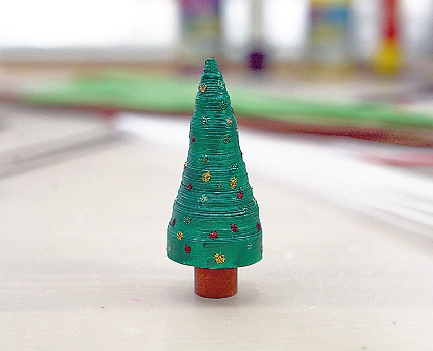 Kırmızı rulo gövde üzerinde renkli noktalarla süslü yeşil koni biçimli quilling çam ağacı