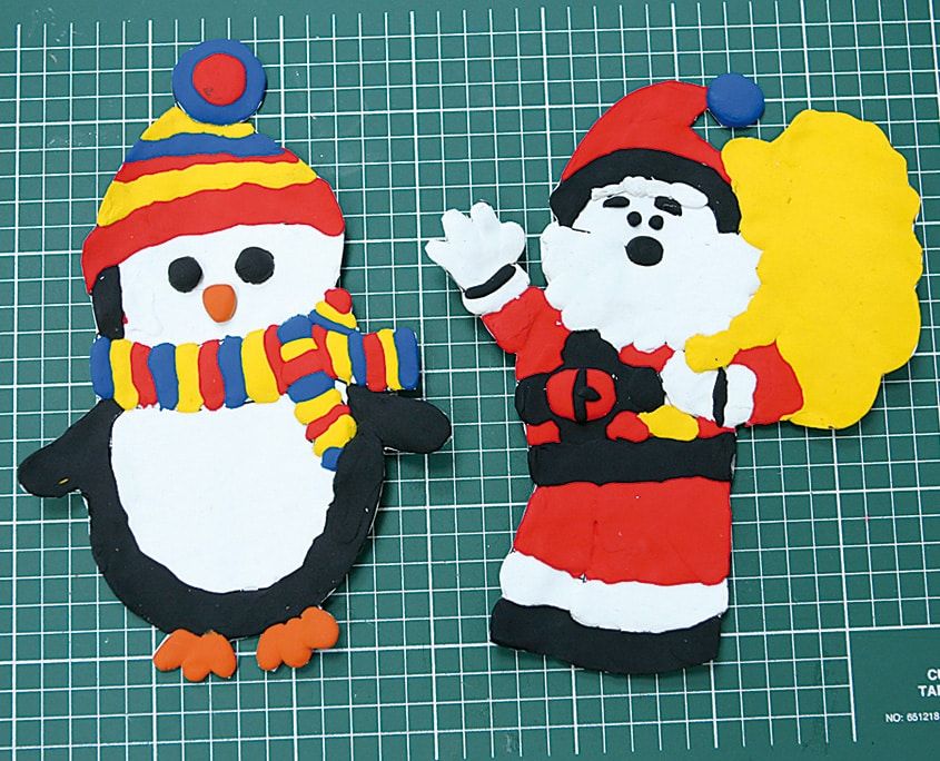 Kenarlarından kesilmiş, kesim matında duran bitmiş hamur penguen ve çuvallı Noel Baba duvar süsleri