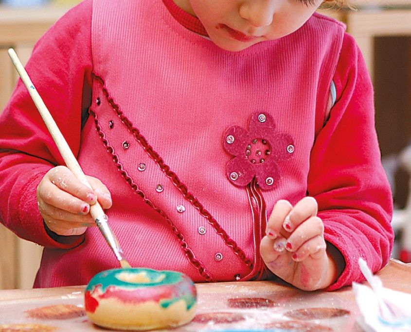 Fırçayla yeşil ve pembe renklere boyanan tuz seramiği halka mumluk yakından