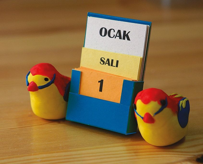 Mavi karton kutuda Ocak, Salı ve 1 kartları, iki yanında sarı-kırmızı hamur kuşlarla masa takvimi