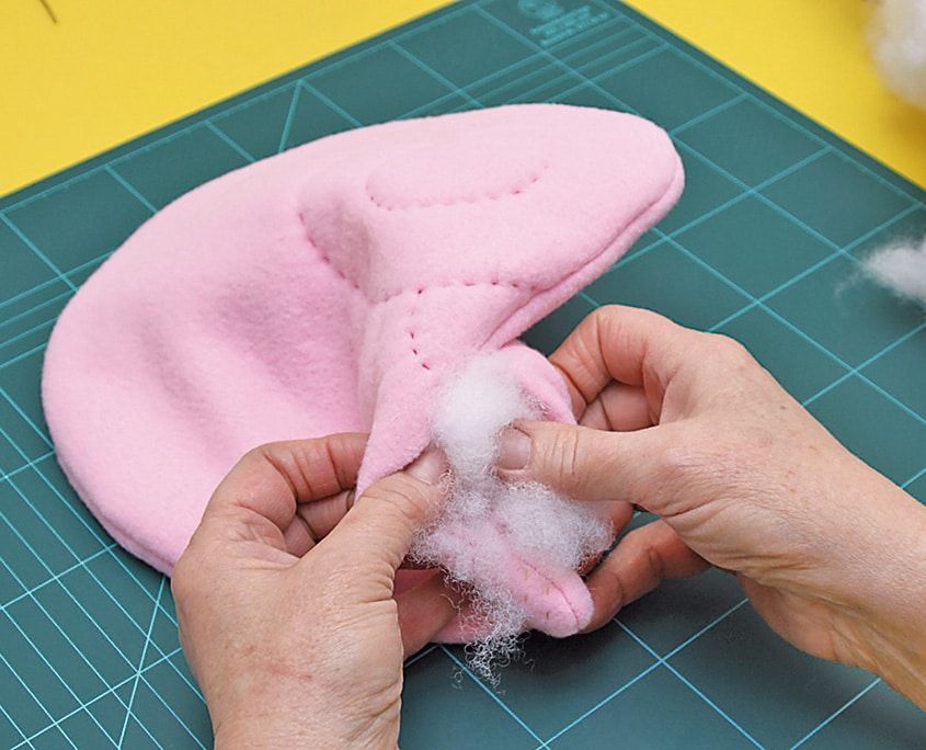 Dikilen pembe kedi gövdesinin açık kalan yerinden içine beyaz elyaf dolgu dolduruluyor