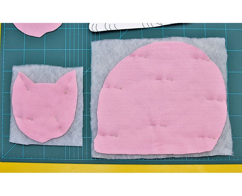 Pembe kumaştan kesilmiş kedi başı ve gövde parçaları, altlarında elyaf vatka katmanı