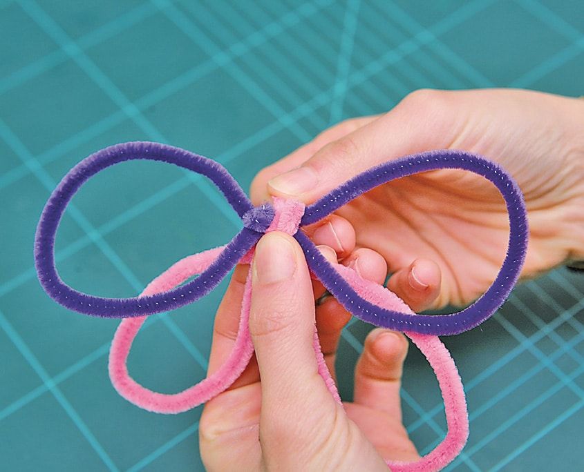 Pembe halkaların üstüne mor tüylü telden ikinci kanat çifti ortadan sarılıyor