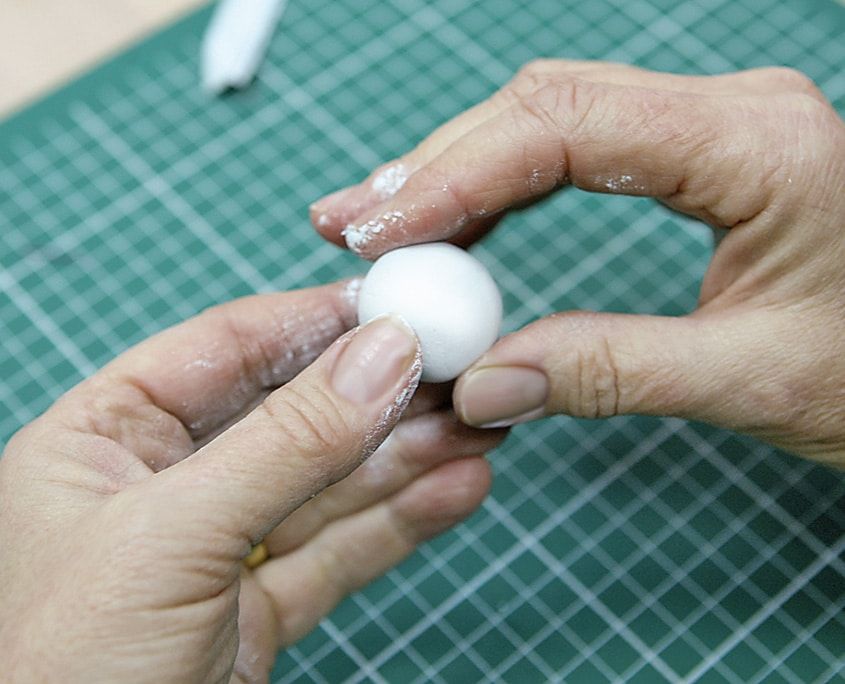 Parmaklar arasında yuvarlanan beyaz top biçiminde hamur, meleğin başı olacak