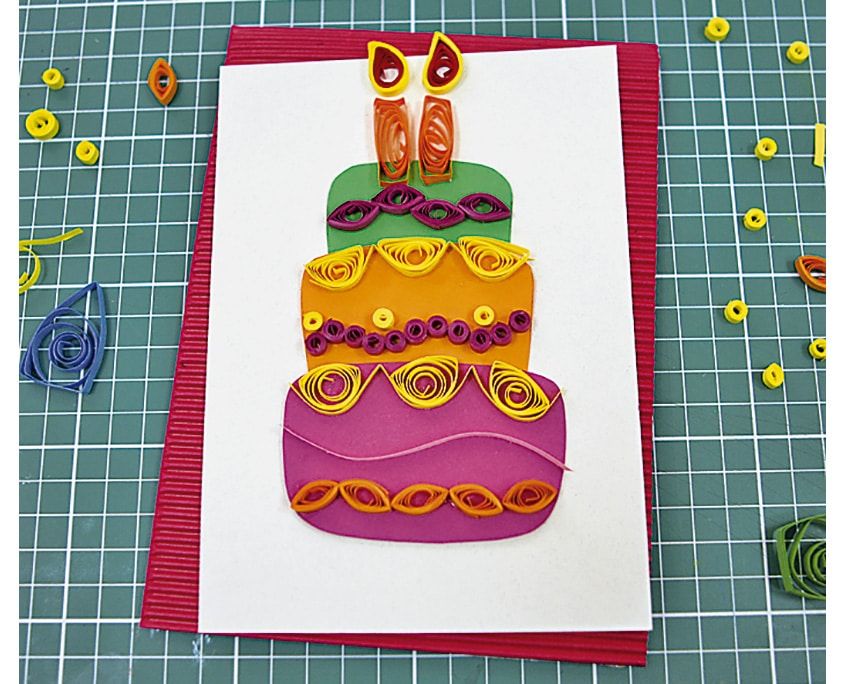 Kırmızı oluklu kartona yapıştırılmış beyaz kağıt üzerinde mumları takılmış quilling pasta