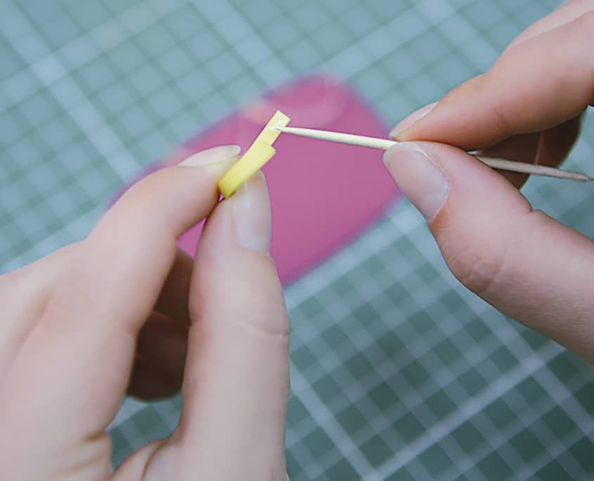 Sarı kağıt şeridin ucunun kürdana sarılmaya başlanması, arkada pembe pasta katı