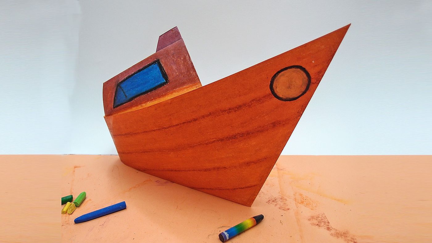 Origami tekne turuncu kağıt zeminde, önünde dağınık duran pastel boyalar ve boya kırıntıları