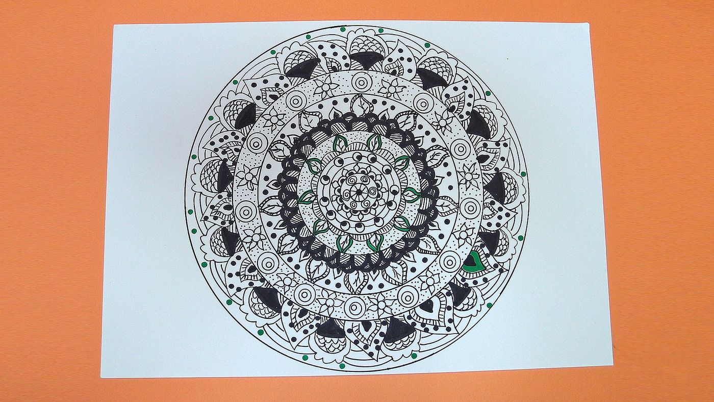 Beyaz kağıda siyah kalemle çizilmiş ayrıntılı dairesel mandala, yaprak ve halka desenleri, turuncu zeminde
