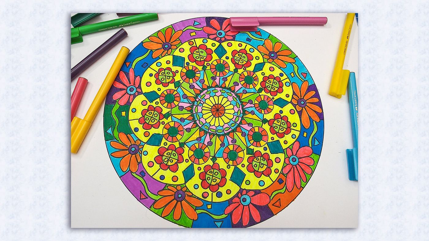 Mandala sarı, kırmızı, mavi ve yeşil keçeli kalemlerle renklendirilmiş, yanında kalemler