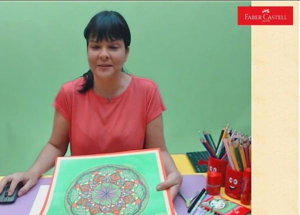 Mandala atölyesi I yayınından kare: eğitmen yeşil kartona yapıştırılmış renkli mandalayı gösteriyor