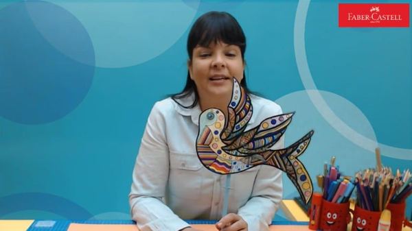Desenli kuş canlı atölyesinden kare: eğitmen çubuğa takılı, renkli desenlerle süslü kuşu gösteriyor