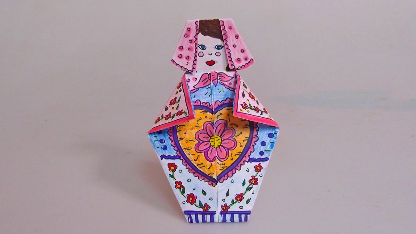 Pembe puantiyeli başörtülü kağıt matruşka, gövdesinde sarı zemin üzerinde pembe kalp çiçek deseni