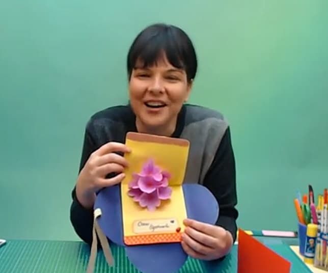 Çiçek kart canlı atölyesinden kare: eğitmen açılır pembe çiçekli sarı kartı zarfıyla gösteriyor