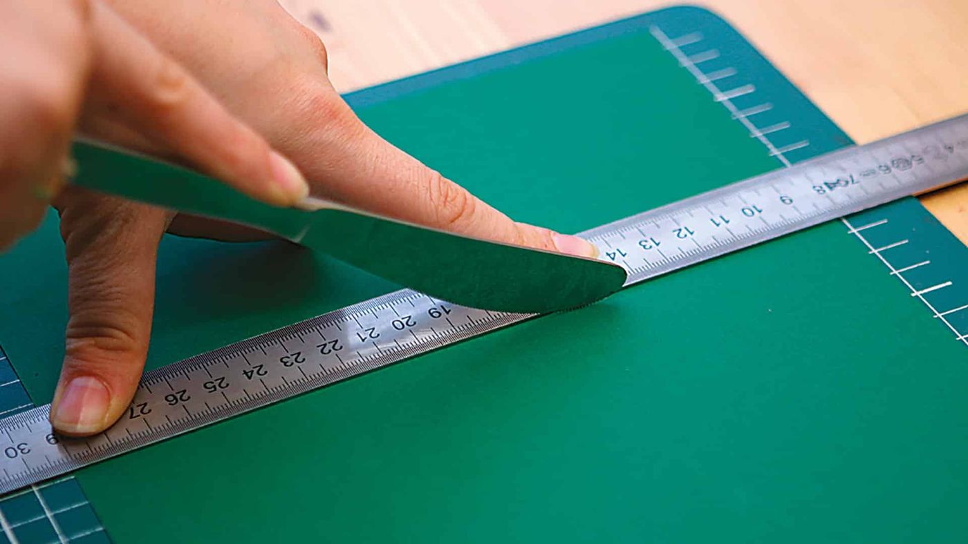 Yeşil karton cetvel yardımıyla ortadan katlanıyor, kesme matı üzerinde