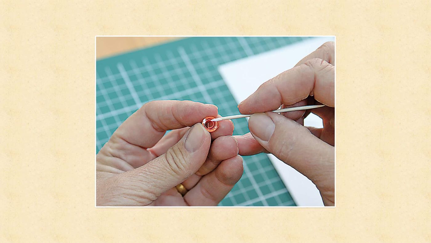 Kürdanın ucunda kırmızı quilling şeridinden sarılmış küçük yuvarlak rulo