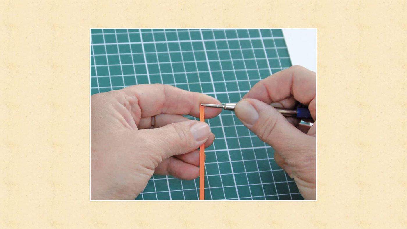 Turuncu quilling şeridinin ucu yarıklı quilling kaleminin ucuna geçiriliyor
