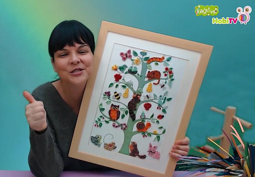 Hayat ağacı quilling video karesi: eğitmen kağıt dolama tekniğiyle yapılmış çerçeveli ağaç tablosunu tutuyor