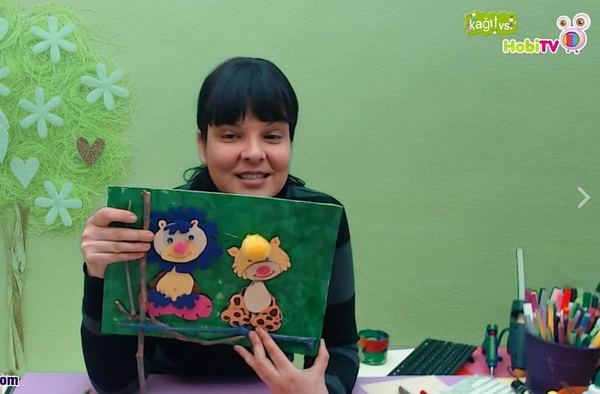 Orman Panosu canlı atölye yayınından kare: eğitmen yeşil zeminli aslan ve leopar panosunu gösteriyor