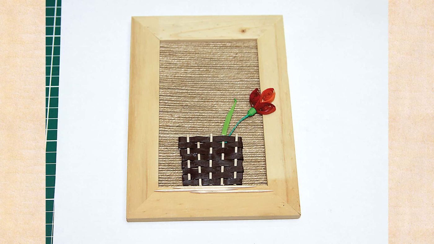 Çerçevedeki örgü sepetin üstüne eklenen ilk kırmızı quilling çiçek ve yeşil sapı