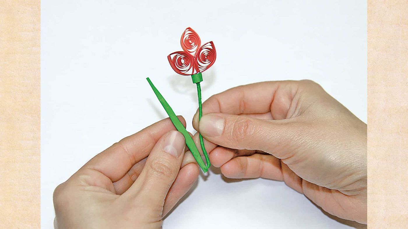 Tamamlanmaya yakın quilling çiçek: bordo taç yapraklar, yeşil sap ve iki uzun yaprak