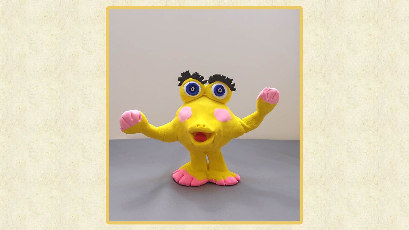 Çerçeve içinde küçük görünen sarı hamur figür Pembe Yanak, gri zemin üzerinde