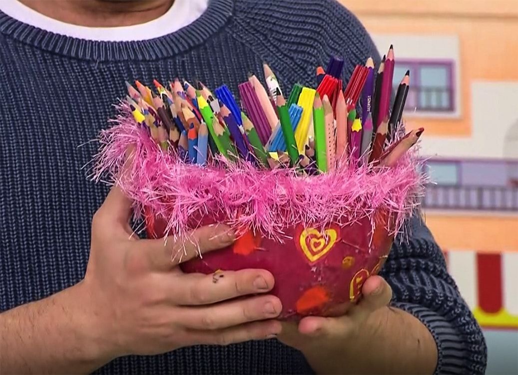 Pembe tüylü kenarlı, kalp desenli kağıt hamuru kaseden kalemlik, renkli kalemlerle dolu
