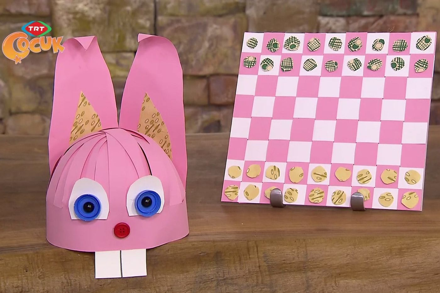Masada pembe tavşan şapka ve yanında yuvarlak taşları dizilmiş pembe beyaz dama tahtası