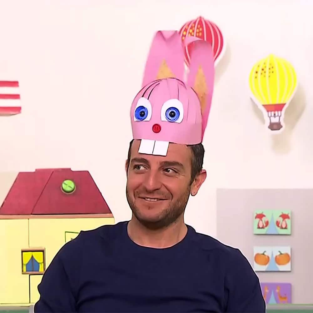 Sunucu pembe tavşan şapka başındayken yana bakıyor, arkada sarı sıcak hava balonu süsü