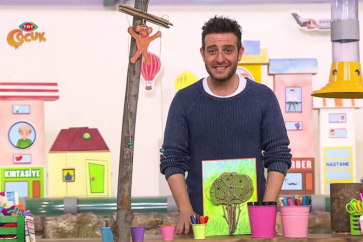 Programdan kare: sunucu ağaç tablosunun yanında, arkada dala tırmanan kağıt maymun