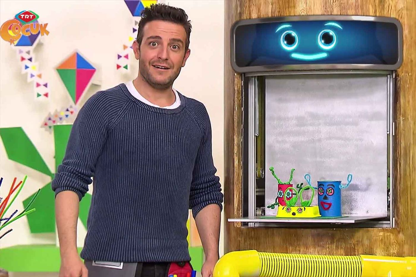 Video karesi: sunucu stüdyoda ayakta, arkadaki pencerede renkli kalemlik bahçesi duruyor